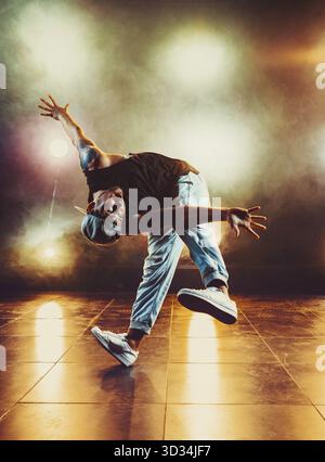 Junger Mann tanzt im Club mit Licht und Rauch. Tätowierung am Körper Stockfoto