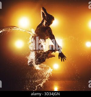 Junger Mann Breakdance-Tänzer mit Lichtern und Wassereffekten. Tattoo zur Hand Stockfoto
