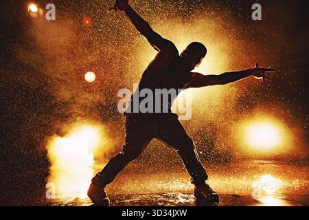 Junger Mann Break Dancer dramatische Silhouette im Club mit Lichtern und Wasser. Tätowierung am Körper Stockfoto