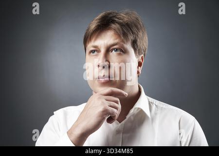 Porträt eines nachdenklichen erwachsenen Mannes, der vor schwarzem Hintergrund wegschaut.isoliert.Studio-Aufnahme Stockfoto