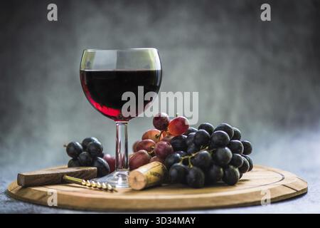 Rotweinglas und frische Trauben und Kork auf Holztafel, Kopierraum oben Stockfoto