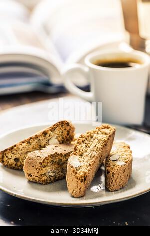 Perfekter Morgen wach, Buch, Espresso und Cantucci auf Holztablett Stockfoto