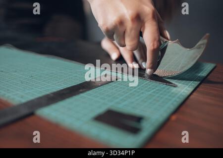 Tanner Frauenhände schneiden Lederwaren in der Werkstatt. Arbeitsprozess des Lederhandwerkers Stockfoto