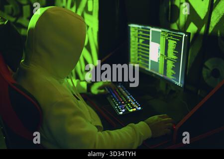 Hacker in der Kapuzenpullover-Funktion hackt Code-Site auf dem PC. Krieg- und Cyberangriffskonzept Stockfoto