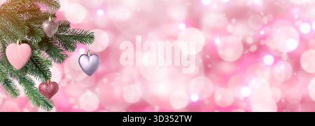 Weihnachtsbaumzweige mit herzförmigen Kugeln vor verschwommenem Licht auf rosa Hintergrund, Bokeh-Effekt. Bannerdesign mit Platz für Text Stockfoto