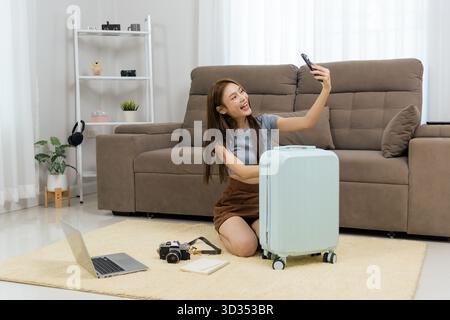 Junge Frau glückliche Aktivität zu Hause lächelt Selfie mit Telefon, sitzt auf dem Boden neben Licht Stockfoto
