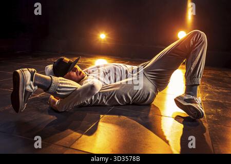 Junger Mann tanzt im Club mit roten Lichtern. Leuchtende Kontrastfarben Stockfoto