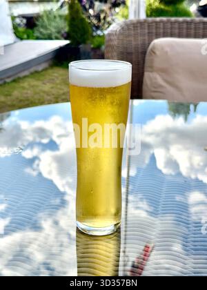Ein Glas kaltes goldenes Lagerbier auf einem Tisch im Garten eines Luxushotels. Keine Personen. Stockfoto