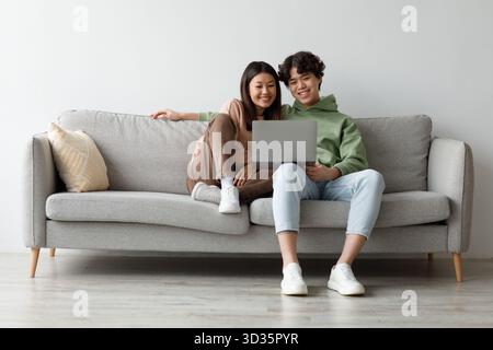 Happy Young Pärchen genießt eine entspannende Zeit auf Sofa mit Laptop zu Hause Stockfoto