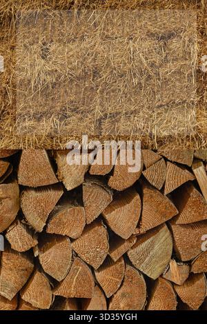 Stapelbarer Brennholzstapel mit Strohabdeckung Stockfoto