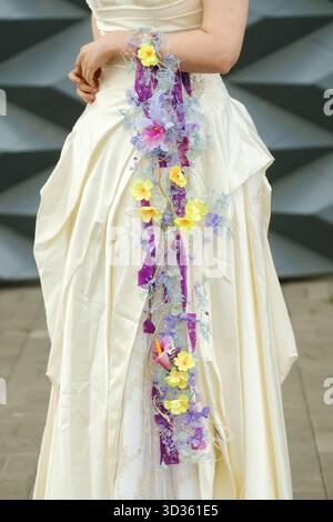 Ein wunderschönes Hochzeitskleid mit aufwändigen Blumendekorationen in leuchtenden Farben. Das Kleid ist im Freien ausgestellt und unterstreicht seine Eleganz während einer Stockfoto