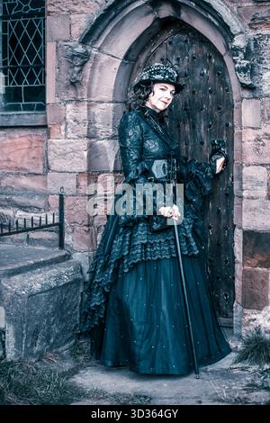 Whitby, England. November 2025. Nahaufnahme Porträt einer Dame in wunderschönen viktorianischen Kleidern und stand an einer Bogentür, St. Mary's Church, im Stockfoto