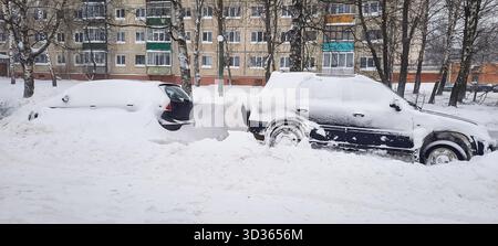 Schneebedeckte Autos nach starkem Schneefall vor Stadthäusern Hintergrund Nahaufnahme selektiver Fokus Stockfoto