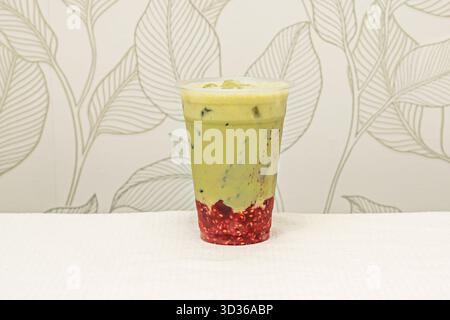 Matcha-Eislatte mit zeremoniellem Matcha-Grüntee, cremiger Kokosmilch und zerstoßenem Eis in einem hohen Glas mit einem umweltfreundlichen Strohhalm Stockfoto