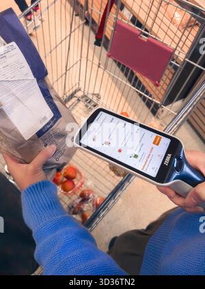 Frau, die einen Scanner zum Scannen von Produkt-Barcodes für Selbstkasse im Sainsbury Supermarkt verwendet, auch bekannt als Scan & Go, Smartshop & Self Checkout, Großbritannien Stockfoto