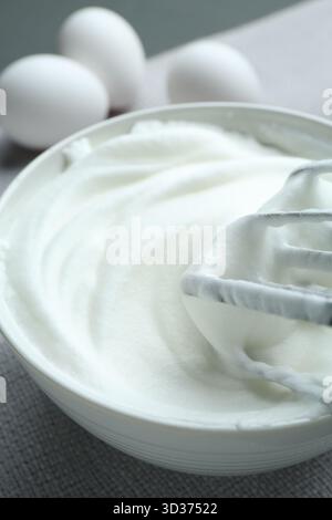 In Schüssel geschlagenes weiß, Mixer und Eier auf dem Tisch, Nahaufnahme Stockfoto