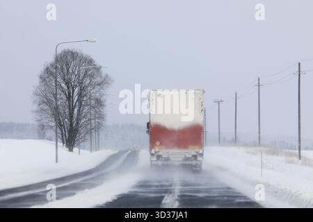 Straßenlandschaft eines Sattelkraftwagens, der an einem Wintertag bei Schneefall auf der Autobahn fährt. Rückansicht, Kopierraum. Stockfoto