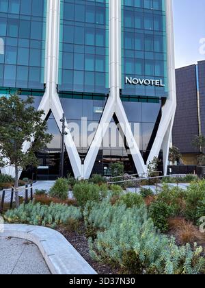 Novotel Auckland Airport Hotel. Modernes, glasverkleidetes Gebäude mit markanten weißen geometrischen Stützen und zeitgenössischer Landschaftsgestaltung am Eingang. Stockfoto