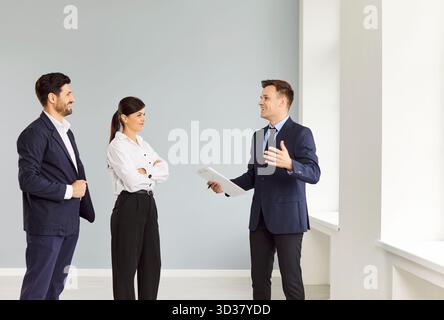 Mann und Frau reden mit Mann Makler in einem neuen Haus und bereit, Hausbesitzer zu werden. Stockfoto