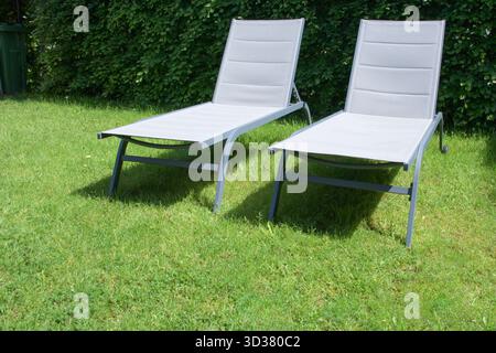 Im Garten stehen an einem Sommertag zwei Liegestühle leer Stockfoto