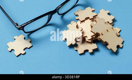 Fokus und Klarheit: Brille in der Nähe eines Puzzleteils und eines Stapels Stockfoto
