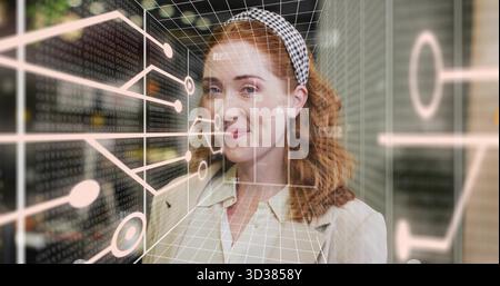 Stehende rothaarige Frau mit Blazer und Stirnband im Büro, das 3D-Schaltungsraster und Binär betrachtet Stockfoto