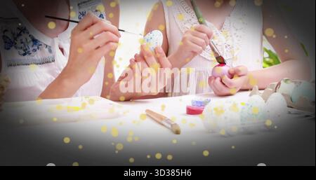 Mutter und Tochter malen Eier auf der Gartenterrasse mit Pinseln und Maltöpfen Stockfoto