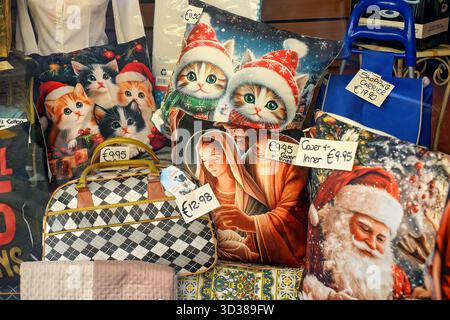 Helles Schaufenster mit dekorativen Kissen mit Kätzchen in Weihnachtshüten, Weihnachtsmann und einer religiösen Szene. Gemütliche festliche Einrichtung und Accessoires Stockfoto