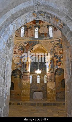 Innenansicht der Antiphonitis-Kirche in Zypern, eingerahmt von einem Steinbogen, mit byzantinischen Fresken und Altar in der Apsis. Stockfoto