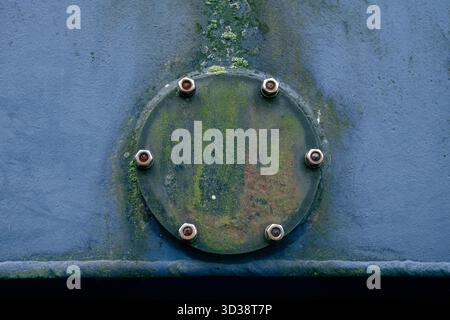 Kreis aus rostfreiem Industriestahl mit Schrauben an blau lackierter Metallplatte, Makro mit Nahbeschaffenheit. Stockfoto