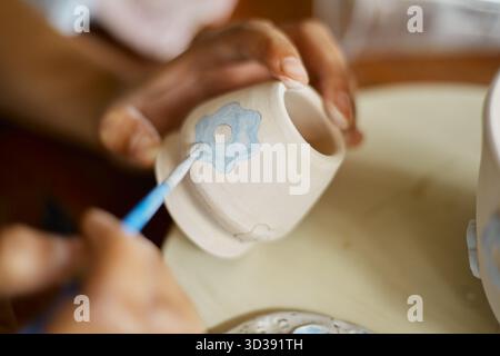 Nahhand einer Frau, die ihre Keramik im Atelier malte. Stockfoto