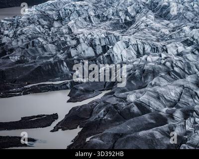 Aus der Vogelperspektive des aschestreibenen isländischen Gletschers mit glazialen Lagunen Stockfoto