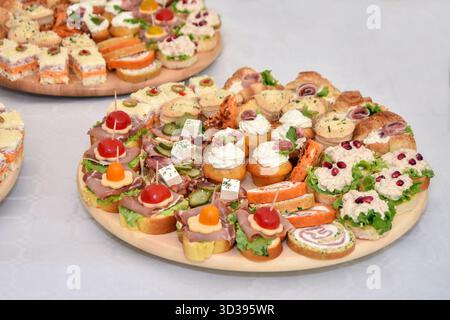 Auswahl an Canapés: Kleine und dekorative Fingerfood auf einem runden Holzteller Stockfoto