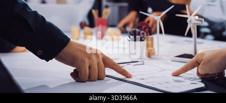 Ein dynamisches Geschäftstreffen in einem modernen Büroumfeld, bei dem Teammitglieder gemeinsam an Projektplänen arbeiten, wobei der Schwerpunkt auf innovativem und nachhaltigem Handeln liegt Stockfoto