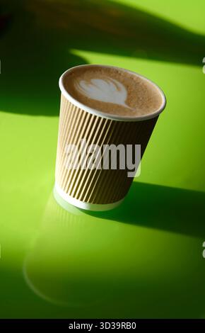 Cortado-Kaffee in Pappbecher auf hellgrüner Tischplatte Stockfoto