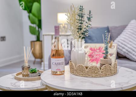 Dekorative Wohnzimmerszene mit Blumenarrangements und einer Flasche Wein auf einem stilvollen Tisch Stockfoto