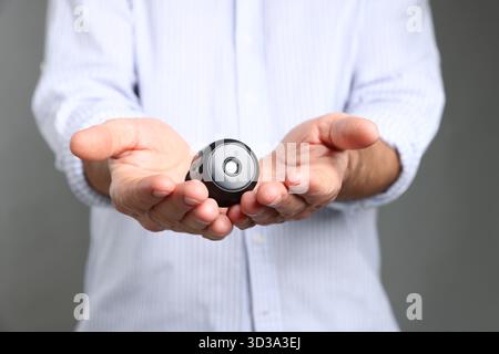 Mann mit versteckter Spionageskamera auf grauem Hintergrund, Nahaufnahme Stockfoto