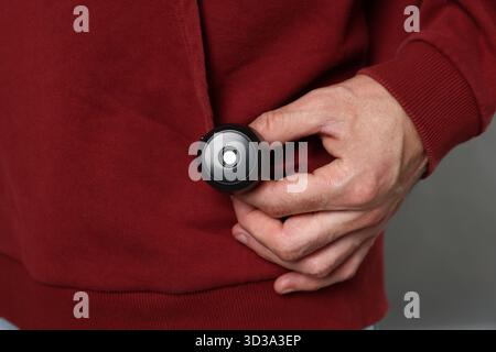 Mann mit versteckter Spionageskamera auf grauem Hintergrund, Nahaufnahme Stockfoto