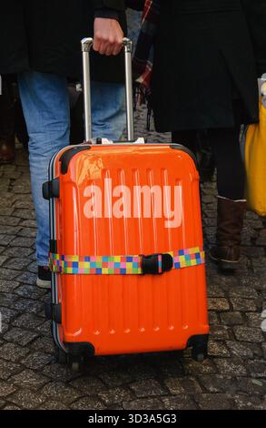 Touristen mit orangefarbenem Gepäck, die auf dem alten Pflastersteinpflaster von Montmartre spazieren. Paris, Frankreich. Stockfoto