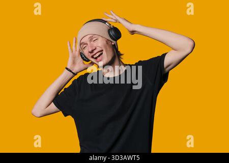 Ein Mann genießt lebhafte Melodie, ein junger Erwachsener taucht in energiegeladene Musik vor lebendigem Hintergrund ein Stockfoto