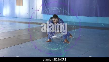 Kampfkünstler mit blauem Gi, der tief auf der Matte hockt, mit digitaler Hologrammkugel Stockfoto