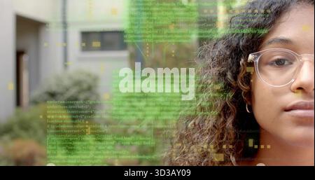 Teenager mit klar gerahmter Brille und Creolen, die Code-Overlay im Innenhof analysieren, Kopierraum Stockfoto