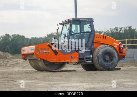 Calgary, Alberta, Kanada. Juni 2025. Eine orangene Hamm H 10i-Verdichterwalze steht auf einer Schotterbaustelle bereit und symbolisiert den schweren Straßenbau und den Straßenbau Stockfoto
