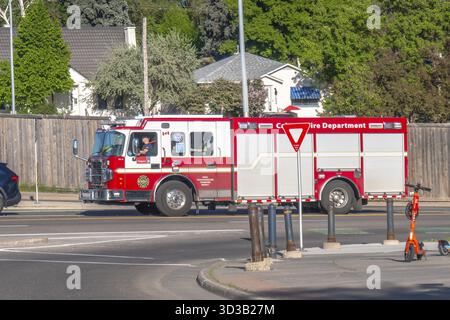 Calgary, Alberta, Kanada. Juni 2025. Ein lebhafter Feuerwehrwagen von Calgary, auffällig rot und weiß, fährt durch eine Wohngegend, repressieren Stockfoto