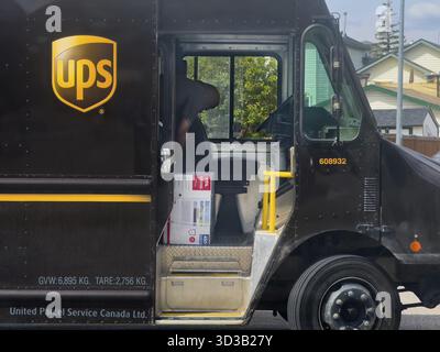 Calgary, Alberta, Kanada. Juni 2025. Ein USV-Lkw parkt mit geöffneter Tür, der Pakete im Inneren und einen Fahrer bei der Arbeit freigibt Stockfoto