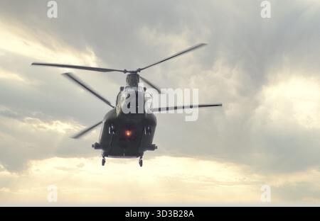 Calgary, Alberta, Kanada. Juni 2025. Ein leistungsstarker Boeing CH-47 Chinook Hubschrauber dominiert den Himmel, dessen Rotoren vor einem dramatischen, bewölkten B verschwimmen Stockfoto