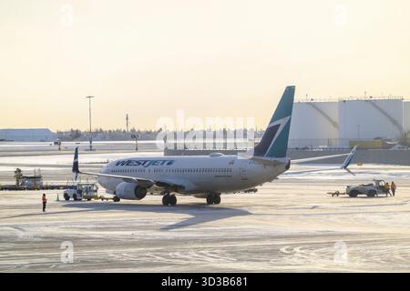Calgary, Alberta, Kanada. Februar 2025. Ein WestJet Boeing 737-800-Flugzeug, das im Winter auf einem verschneiten Asphalt auf einem internationalen Flughafen von Calgary geparkt wurde Stockfoto