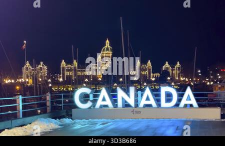 Victoria, British Columbia, Kanada. Februar 2025. Ein Nachtfoto von beleuchteten KANADISCHEN Briefen vor dem hell erleuchteten British Columbia Parliament Stockfoto
