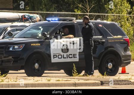 Calgary, Alberta, Kanada. September 2024. Zwei Polizeibeamte in Calgary sind an einer Diskussion beteiligt, neben einem markierten Polizei-SUV, mit einem Polizisten in der Stockfoto