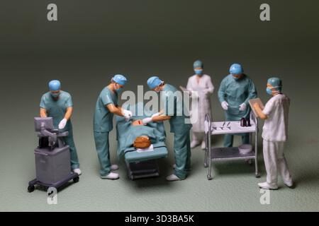 Miniaturmenschen, medizinisches Personal Chirurgie Szene in Bearbeitung, die Figuren werden in Peelings, Gesichtsmasken und Kappen gekleidet, typisch für eine OP-RO Stockfoto